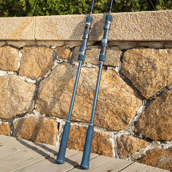 Monster Deep spinning and casting handles with dark blue EVA grips against a stone wall